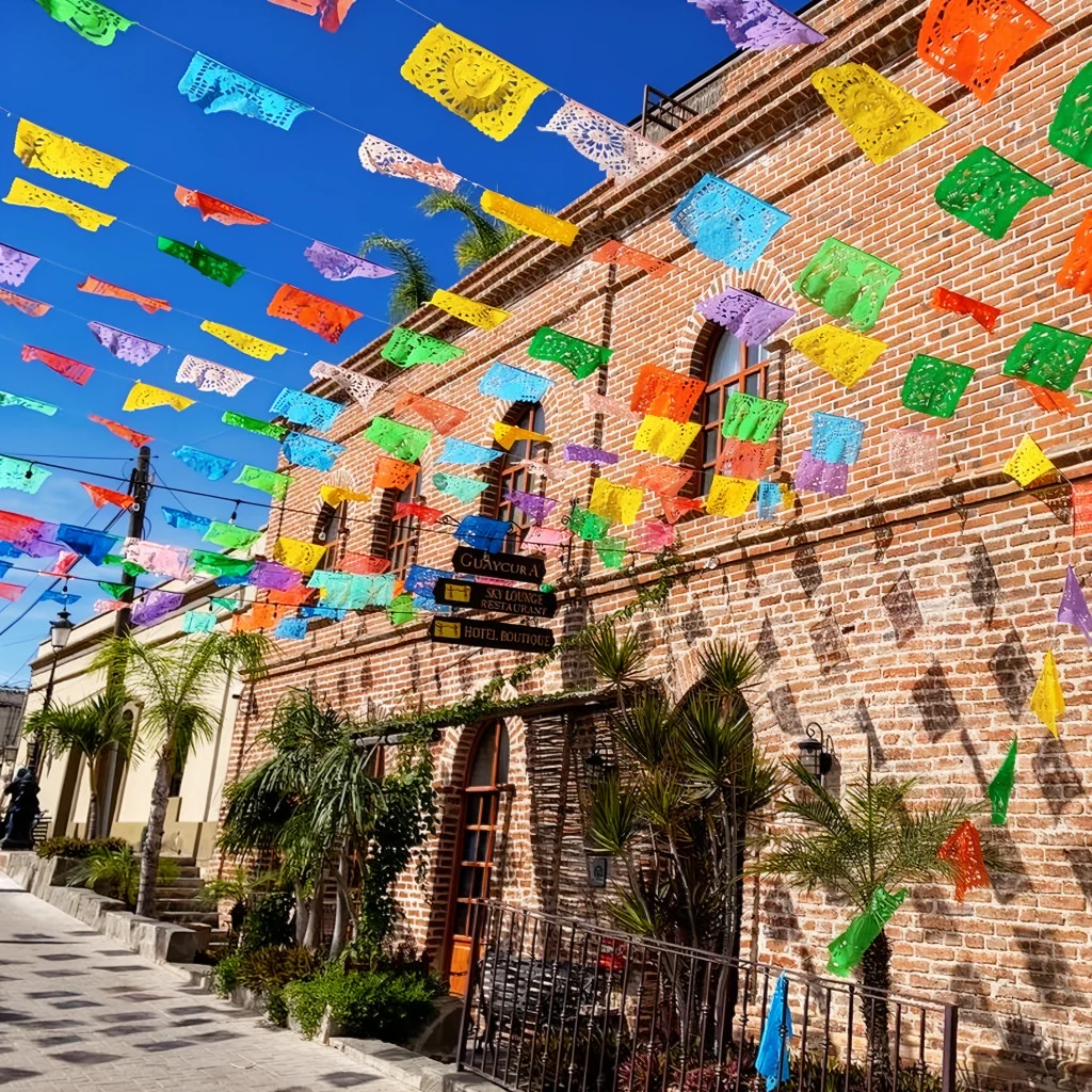 Papel picado over a brick street in the historic centre of Todos Santos